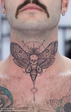 a man's chest with a moth tattoo on it and a skull in the middle