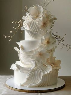 a three tiered white wedding cake with flowers on top