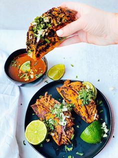 a plate with some tacos on it next to a bowl of salsa and lime wedges