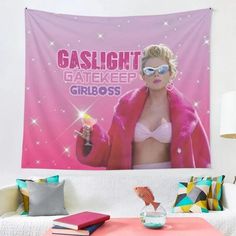 a pink wall hanging over a white couch in a living room with a poster on the wall