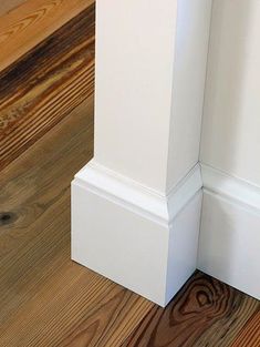 the corner of a white column with wood flooring