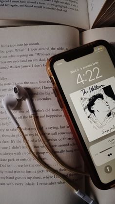 an open book with headphones on top of it next to earbuds and a cell phone