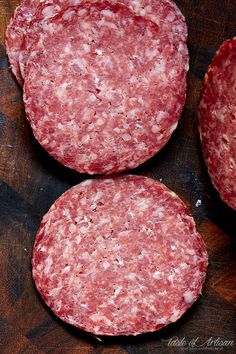 three hamburger patties sitting on top of a wooden cutting board