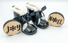 a pair of black boots with snowflakes on them and a wooden name tag