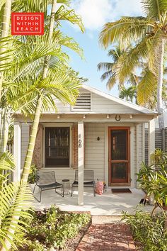 a small white house with palm trees in the front yard and red sign that says detent main