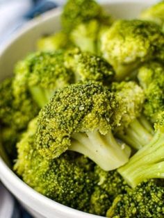 a white bowl filled with broccoli on top of a table