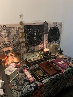 a table topped with lots of books next to a candle and pictures on the wall