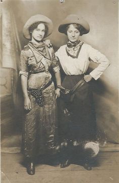 an old photo of two women standing next to each other with hats on their heads