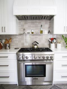 a stove top oven sitting inside of a kitchen next to white cabinets and counter tops