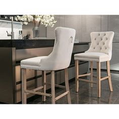 two white bar stools sitting in front of a counter