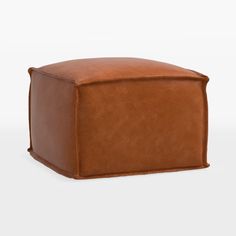 a brown leather ottoman sitting on top of a white floor