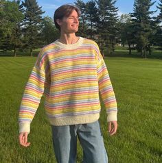 a man standing in the grass wearing a colorful sweater