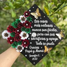 a graduation cap with flowers on it is being held in the air by someone's hand