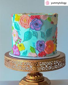 a multi - colored cake decorated with flowers on a gold stand