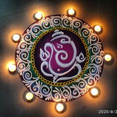 an illuminated diya with the word om written on it and lit candles around it