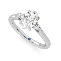 a white gold ring with three pear shaped diamonds and blue sapphires on the side