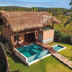 an aerial view of a house with a pool in the yard and thatched roof