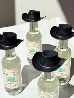 three bottles with black hats on them sitting on a white tablecloth and one bottle is empty