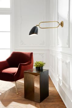 a red chair sitting next to a table with a potted plant on top of it