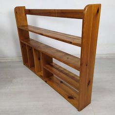 a wooden shelf sitting on top of a white floor next to a wall with shelves