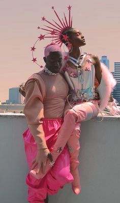 two people sitting on top of a wall next to each other wearing pink outfits and headgear