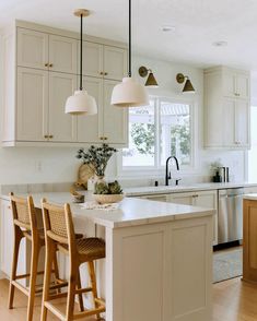 a kitchen with white cabinets and wooden stools