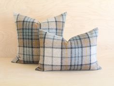 two plaid pillows sitting on top of a wooden table next to each other, one is blue and the other is yellow