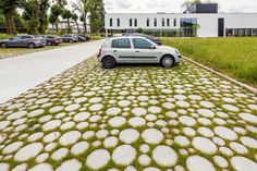 a car parked in front of a building with grass growing on the ground and cobblestone pavement