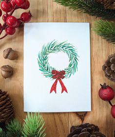 a card with a christmas wreath and red bow on it, surrounded by pine cones