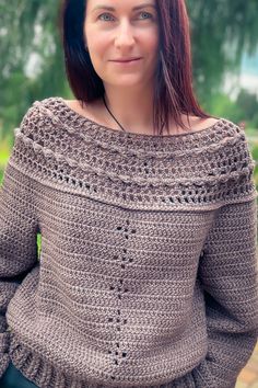 a woman with red hair wearing a brown crochet sweater and smiling at the camera