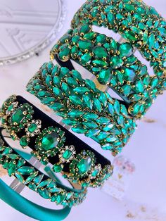 green bracelets are stacked on top of each other with gold and crystal beads around them