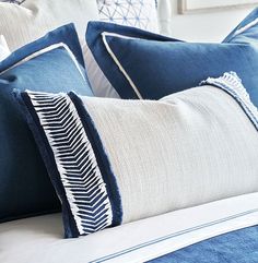 a bed with blue and white pillows on top of it next to a framed picture