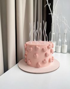 a pink cake sitting on top of a white table