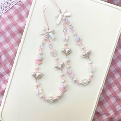 two necklaces with hearts and crosses on them sitting on a table next to a pink gingham cloth