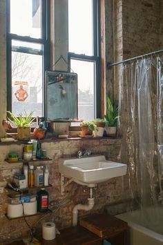 a bathroom with exposed brick walls and large windows