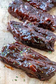 two pieces of bbq ribs sitting on top of a wooden cutting board