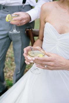 the bride and groom are holding their glasses with lemon wedges in each hand while standing next to each other