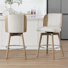 two white stools sitting in front of a kitchen counter with a potted plant on it