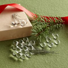 a present box and some glass beads next to a red ribbon on a green surface