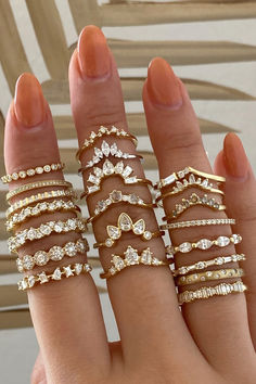 a woman's hand with five different rings on her fingers, all in gold