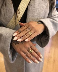 a woman with tattoos on her hands holding onto another person's arm and wearing a coat