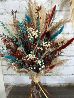 a vase filled with lots of different types of flowers next to a white brick wall