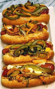 three hot dogs on buns with peppers and onions in them sitting on a white plate