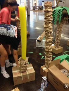 a woman standing next to cardboard boxes with palm trees on them and other items in front of her