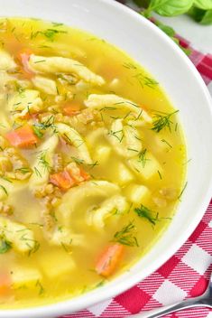 a white bowl filled with chicken noodle soup on top of a red and white checkered table cloth