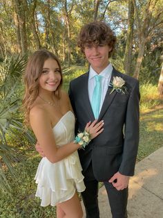 a young man and woman dressed in formal wear standing next to each other