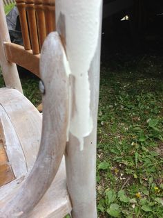 an old wooden rocking chair sitting in the grass with peeling paint on it's arm