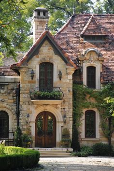 an old stone house with ivy growing on it's windows and door, surrounded by greenery