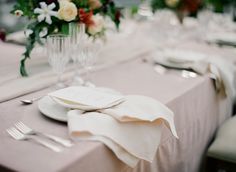 the table is set with white plates and silverware, napkins, and flowers