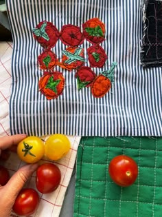 tomatoes and other vegetables are on the table next to a quilted bag with an embroidered design